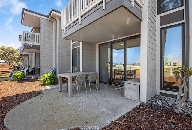 view of patio with a balcony and outdoor dining space