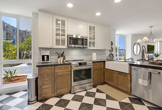 kitchen with stainless steel appliances, a sink, dark countertops, backsplash, and recessed lighting