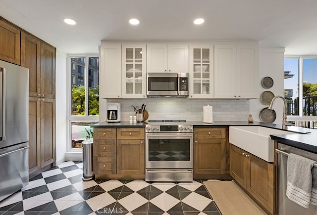 kitchen featuring appliances with stainless steel finishes, a sink, tasteful backsplash, white cabinetry, and recessed lighting