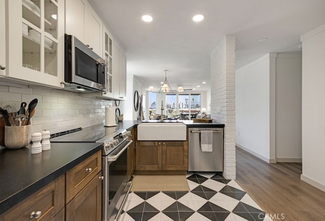 kitchen with appliances with stainless steel finishes, a sink, backsplash, dark countertops, and recessed lighting