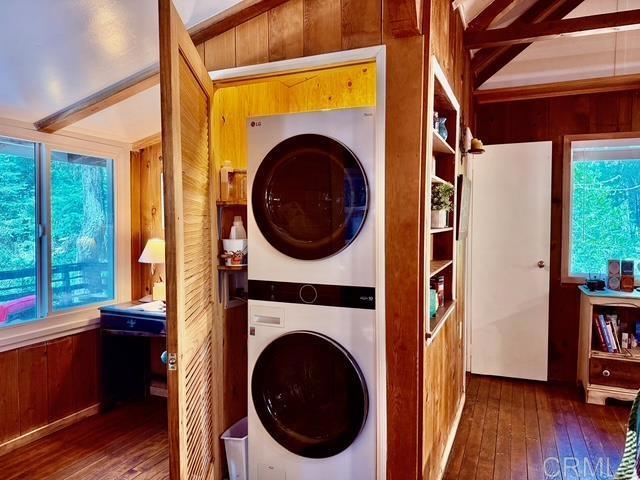 22104 Crestline, Palomar Mountain, CA 92060 - clothes washing area featuring stacked washing machine and dryer, hardwood / wood-style floors, and wooden walls