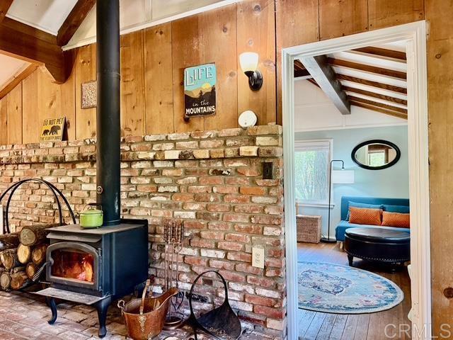 22104 Crestline, Palomar Mountain, CA 92060 - detailed view of beamed ceiling, a wood stove, wooden walls, and wood finished floors