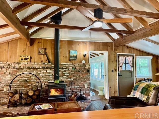 22104 Crestline, Palomar Mountain, CA 92060 - living area featuring hardwood / wood-style floors, plenty of natural light, wooden walls, and a wood stove