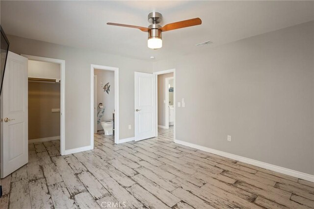 618 E Sunset Dr N, Redlands, CA 92373 - unfurnished bedroom with a walk in closet, wood finished floors, a closet, and a ceiling fan