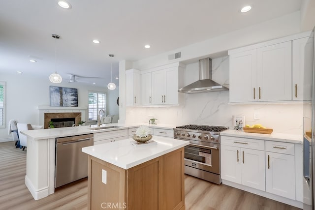 2115 Via Viejo, San Clemente, CA 92673 - kitchen featuring appliances with stainless steel finishes, wall chimney exhaust hood, a sink, a peninsula, and light wood-type flooring