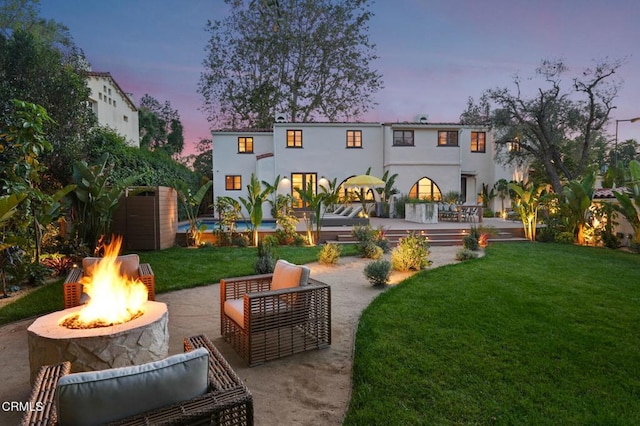 620 S Allen Ave, San Marino, CA 91108 - back of property at dusk featuring a patio area, a yard, stucco siding, an outdoor living space with a fire pit, and a wooden deck