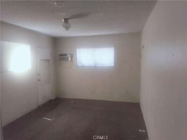 carpeted spare room with a wall mounted air conditioner and a textured ceiling