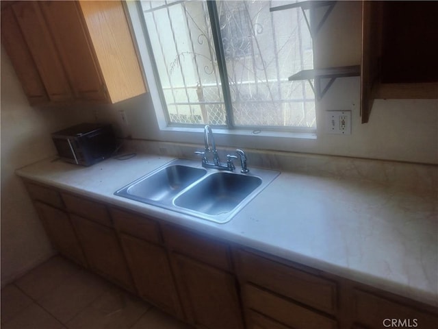 kitchen with a sink, light countertops, and brown cabinets