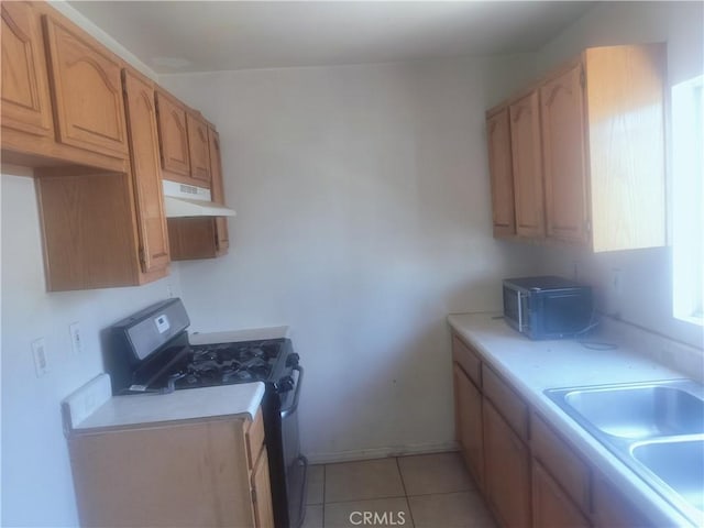 kitchen featuring stainless steel range with gas stovetop, under cabinet range hood, light countertops, and a sink