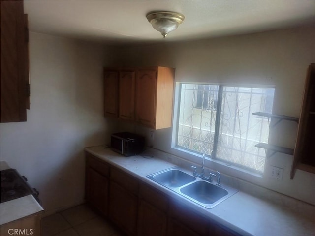 kitchen featuring a sink, light countertops, stainless steel microwave, and open shelves