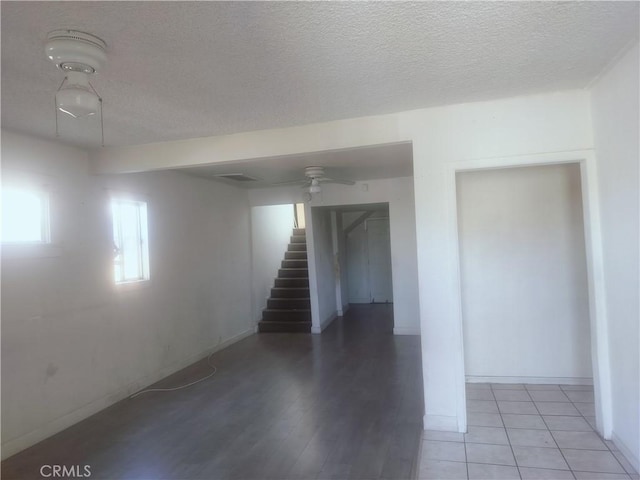 below grade area with stairs, a textured ceiling, ceiling fan, and baseboards