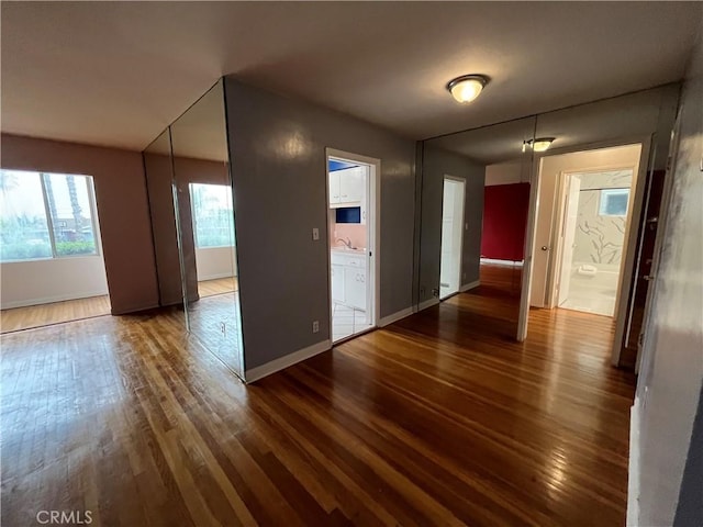 spare room featuring wood finished floors, baseboards, and a sink