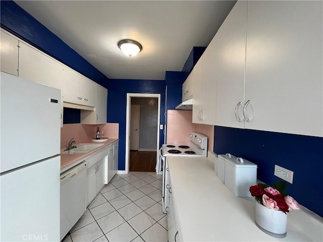 kitchen featuring white appliances, a sink, under cabinet range hood, light countertops, and white cabinetry