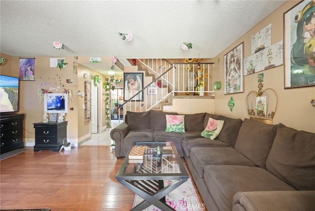 living area featuring a textured ceiling, stairway, wood finished floors, and baseboards