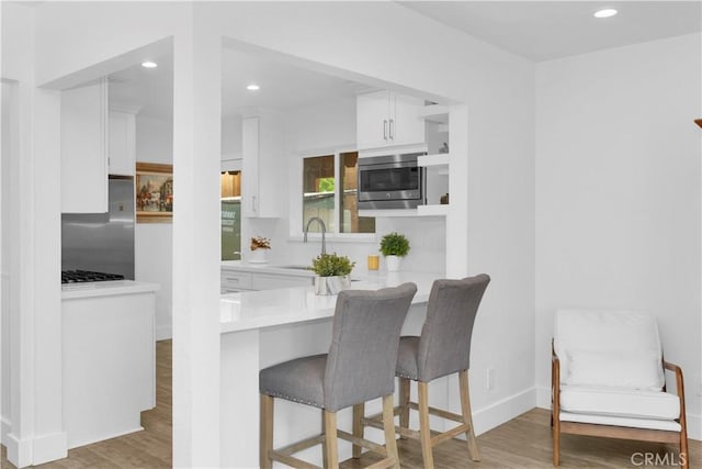 5314 E 4th St, Long Beach, CA 90814 - kitchen featuring appliances with stainless steel finishes, a sink, white cabinets, a breakfast bar area, and recessed lighting