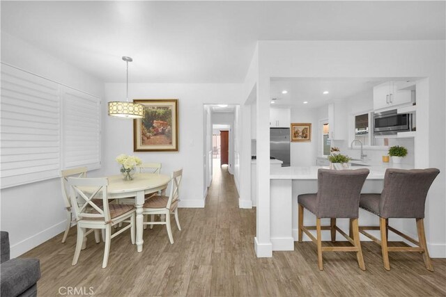 5314 E 4th St, Long Beach, CA 90814 - kitchen with built in appliances, white cabinets, wood finished floors, light countertops, and recessed lighting