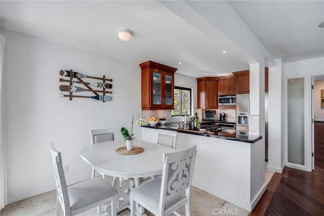 kitchen with stainless steel microwave, decorative backsplash, dark countertops, glass insert cabinets, and recessed lighting