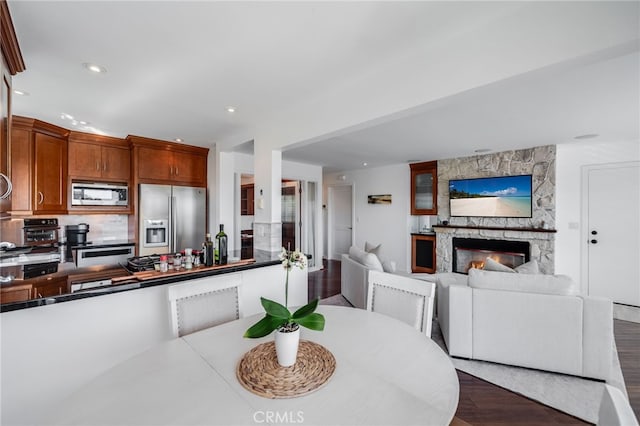 dining space with dark wood-type flooring, a large fireplace, and recessed lighting