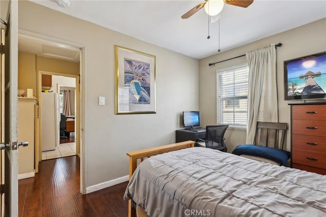 bedroom featuring baseboards, dark wood finished floors, freestanding refrigerator, and ceiling fan