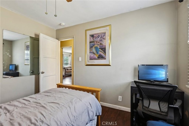 bedroom with dark wood finished floors, baseboards, an office area, and a ceiling fan
