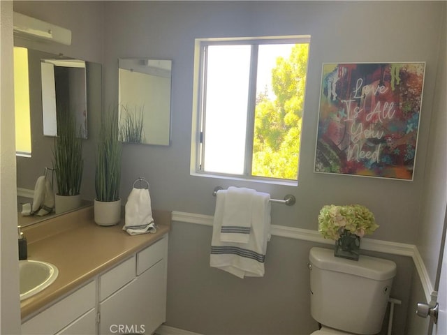 bathroom with toilet, vanity, and baseboards