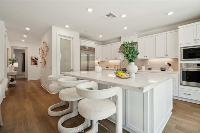 26288 Meadow Dr, San Juan Capistrano, CA 92675 - kitchen featuring built in appliances, recessed lighting, a kitchen island with sink, light countertops, and white cabinets
