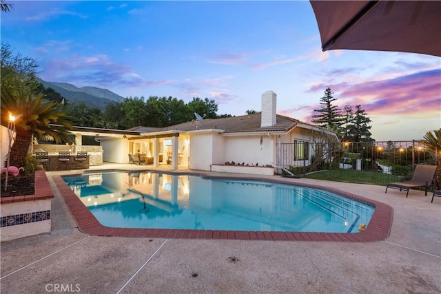 outdoor pool featuring a patio area, area for grilling, fence, and a mountain view