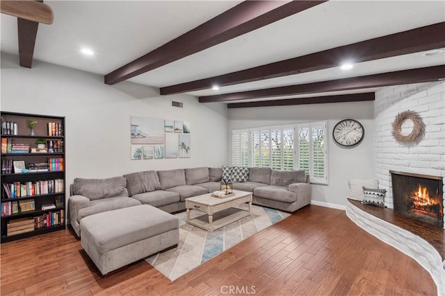 living area with light wood-style flooring, beam ceiling, baseboards, a brick fireplace, and recessed lighting