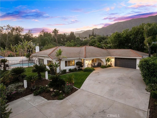 view of front of home featuring concrete driveway, a tile roof, an attached garage, a mountain view, and stucco siding
