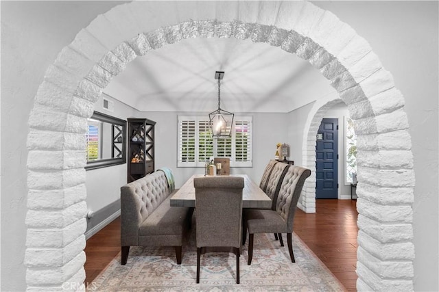 dining room featuring wood finished floors, arched walkways, and baseboards