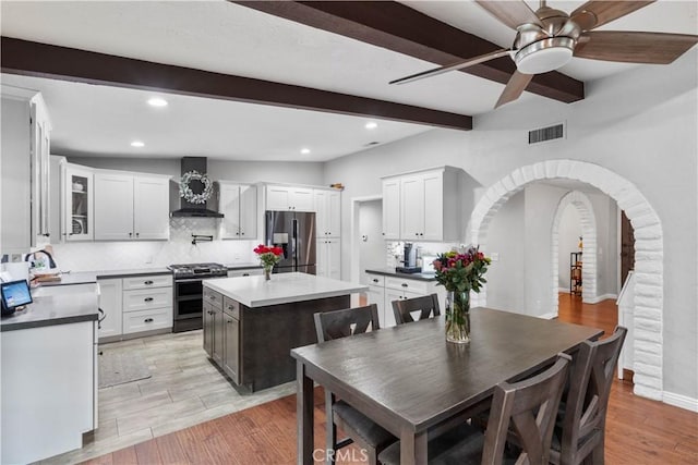 dining area with beamed ceiling, ceiling fan, light wood-style floors, arched walkways, and recessed lighting