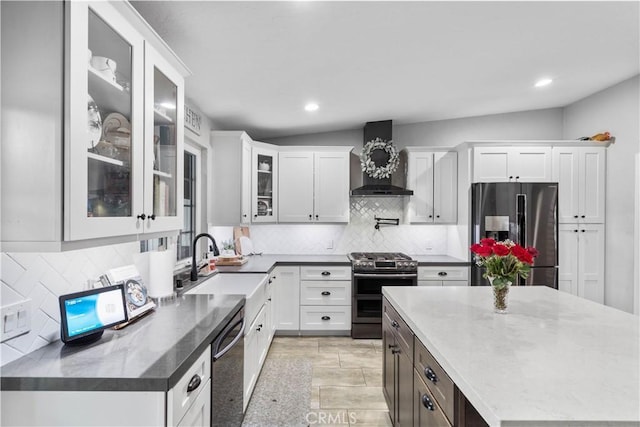 kitchen with appliances with stainless steel finishes, wall chimney exhaust hood, a sink, decorative backsplash, and white cabinets