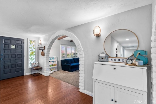 entrance foyer with wood finished floors, baseboards, and arched walkways