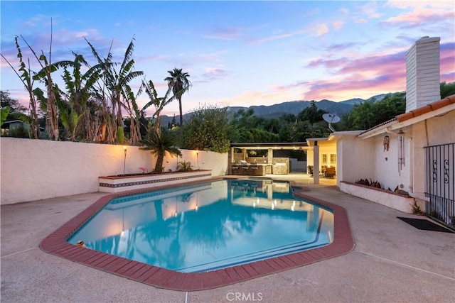 view of pool with a fenced backyard, a mountain view, a patio area, and an outdoor kitchen