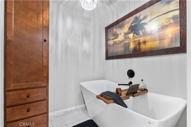 full bathroom featuring a freestanding tub, baseboards, and marble finish flooring
