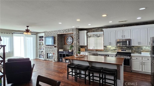 13817 Grant Way, Oak Hills, CA 92344 - kitchen with stainless steel appliances, butcher block countertops, healthy amount of natural light, a kitchen bar, and a textured ceiling