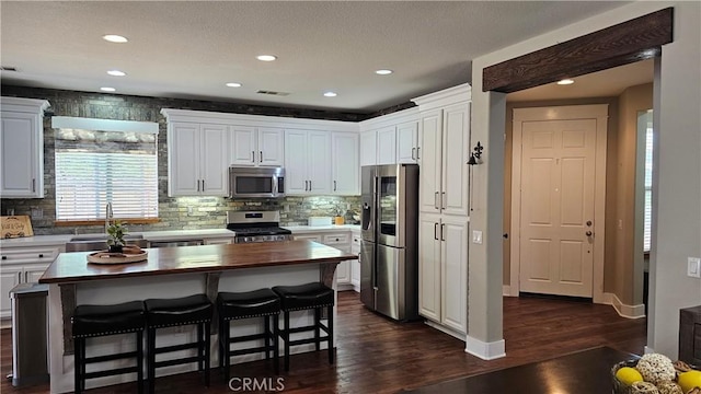 13817 Grant Way, Oak Hills, CA 92344 - kitchen with stainless steel appliances, butcher block counters, a sink, dark wood-style flooring, and white cabinetry