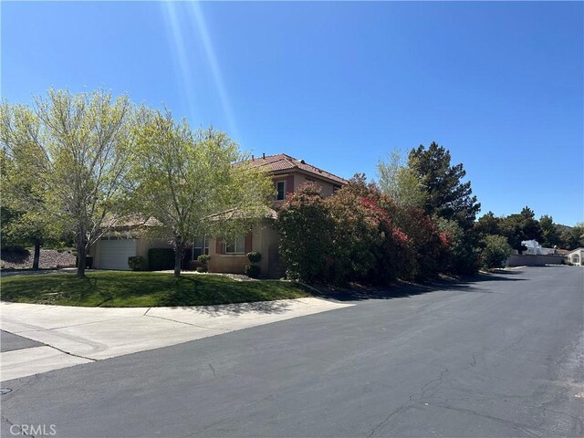 41053 Knoll Dr, Palmdale, CA 93551 - view of property hidden behind natural elements featuring a front yard, stucco siding, and an attached garage