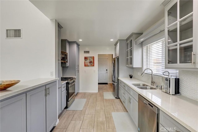 8910 S 3rd Ave, Inglewood, CA 90305 - kitchen featuring stainless steel appliances, a sink, gray cabinetry, decorative backsplash, and light countertops