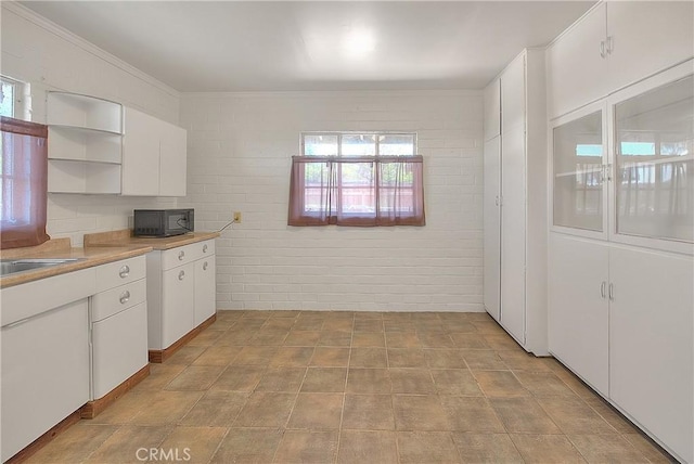 321 Aguirre Ln, Placentia, CA 92870 - kitchen with black microwave, healthy amount of natural light, white cabinetry, and ornamental molding