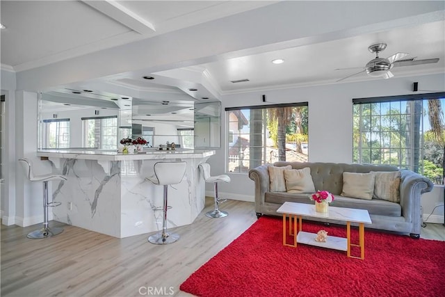 living area featuring wood finished floors, ornamental molding, plenty of natural light, baseboards, and recessed lighting