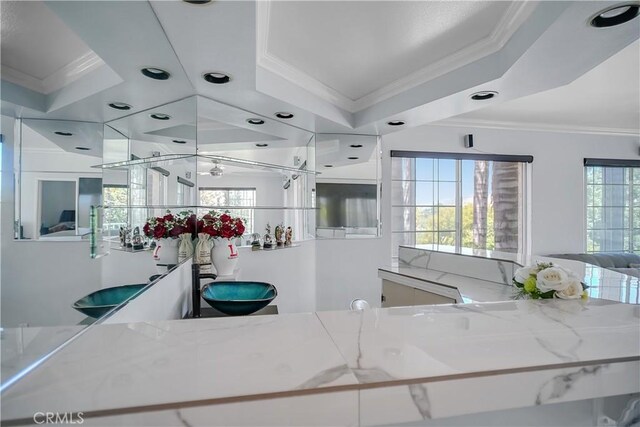 kitchen featuring ornamental molding, open floor plan, and light stone countertops
