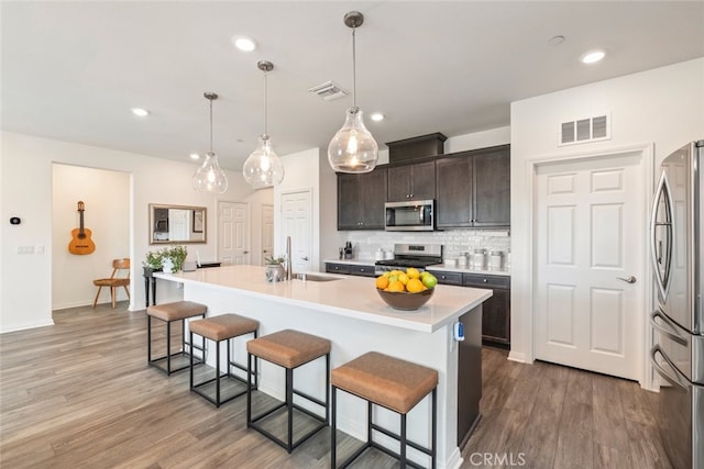 41215 Alegria Ln, Lake Elsinore, CA 92532 - kitchen featuring appliances with stainless steel finishes, a sink, a kitchen breakfast bar, backsplash, and wood finished floors