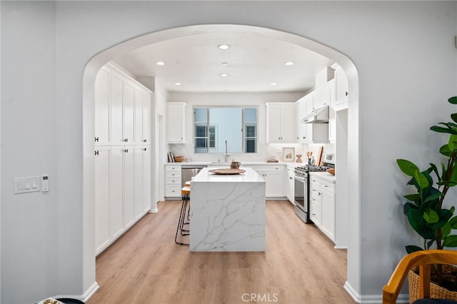 kitchen featuring appliances with stainless steel finishes, under cabinet range hood, light wood finished floors, white cabinetry, and recessed lighting