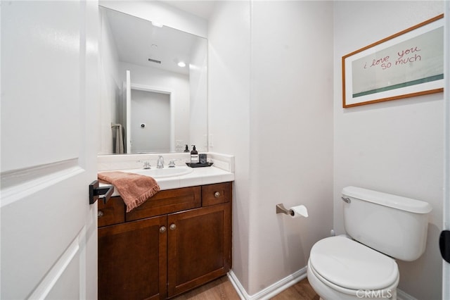 bathroom with toilet, wood finished floors, and vanity