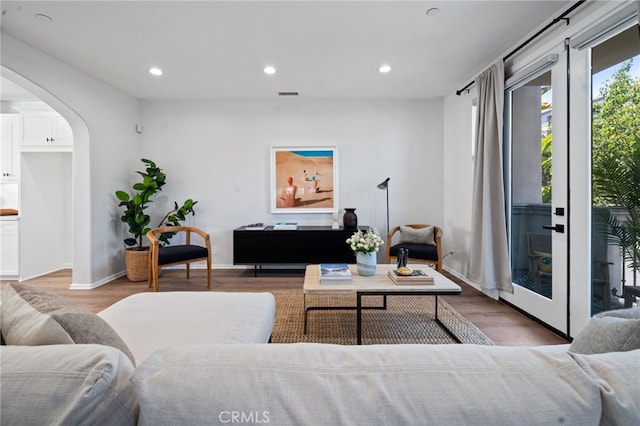 living area with arched walkways, wood finished floors, recessed lighting, and baseboards
