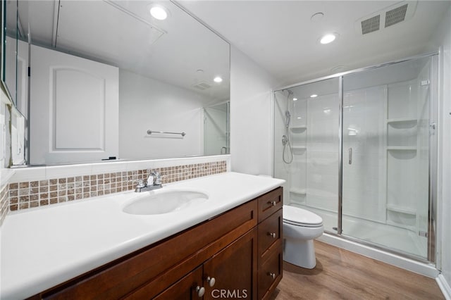 bathroom featuring wood finished floors, toilet, a stall shower, backsplash, and recessed lighting