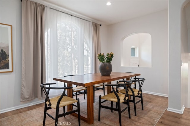 dining area featuring arched walkways, wood finished floors, baseboards, and recessed lighting