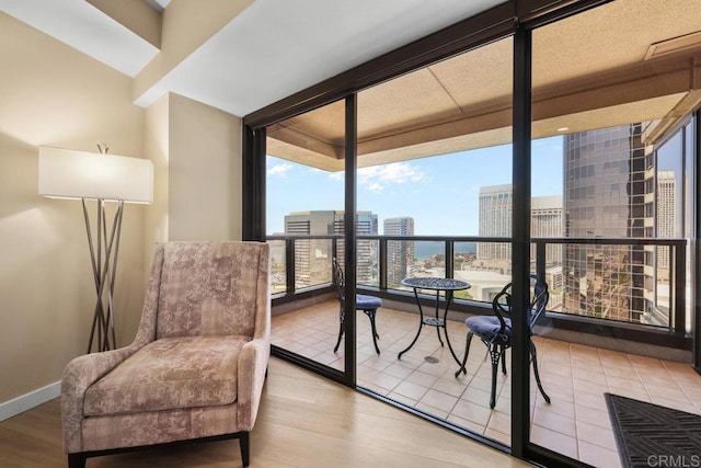 sitting room featuring healthy amount of natural light, a view of city, wood finished floors, and a wall of windows