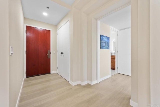 hall with light wood-type flooring and baseboards